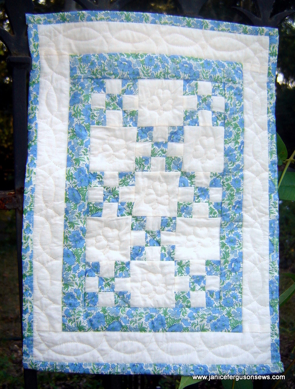 This little quilt appears misshapen because it is being held in place by a vine stub and a prong on the wrought iron arch and is poked out of shape.  